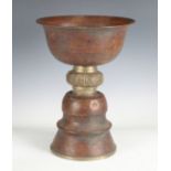 A 19th century Tibetan copper butter lamp, the waisted brass mid-section cast with fish and food-