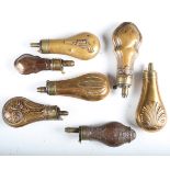 A group of seven 19th century copper and brass powder flasks, all with embossed decoration,