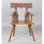 An early 19th century Continental walnut sgabello armchair, the shaped back finely carved with a