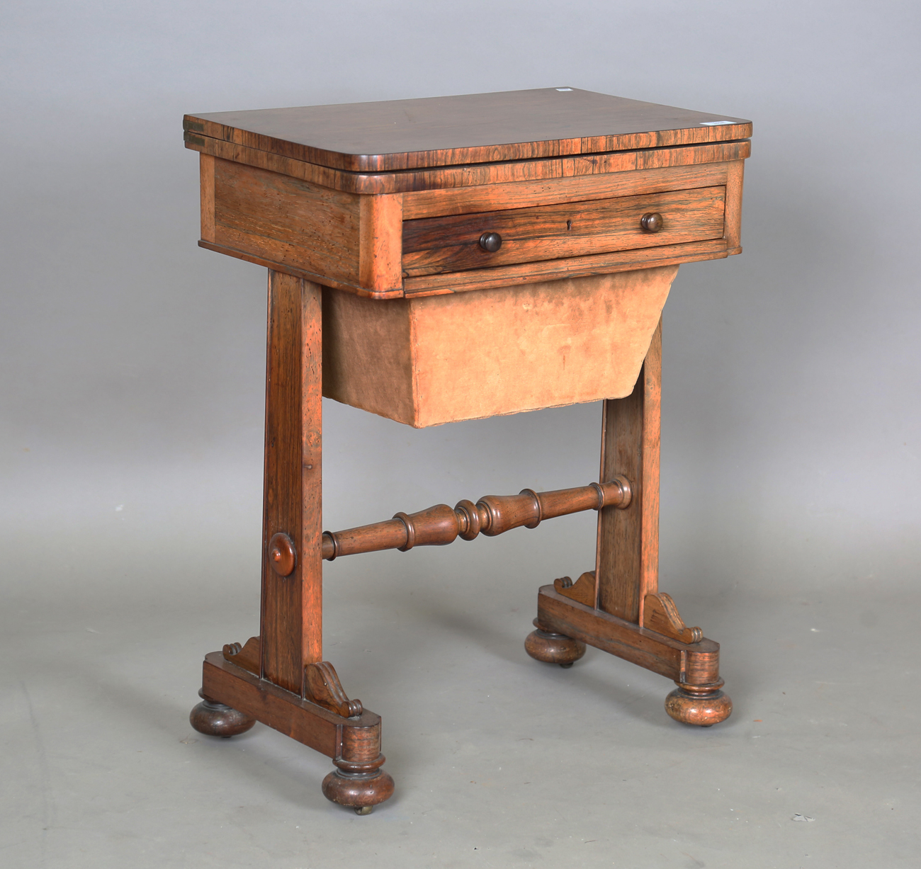 A Victorian rosewood work table, the top hinged to reveal a surface inset with leather above a