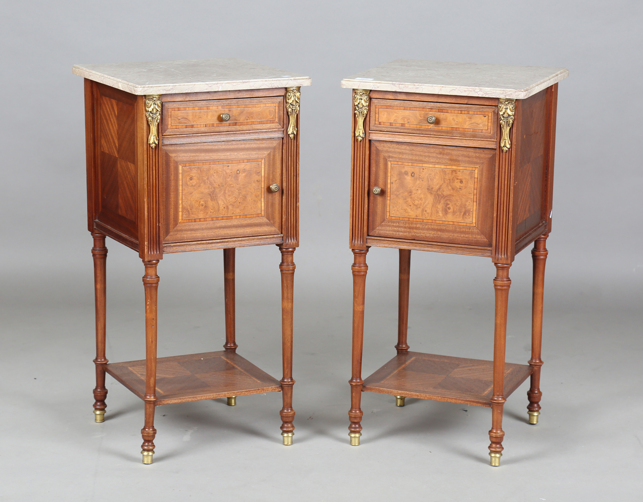 A pair of early 20th century French marble-topped bedside cabinets with ormolu mounts and ceramic-