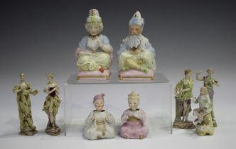 A pair of Continental bisque porcelain nodding head figures, circa 1900, seated cross-legged on pink