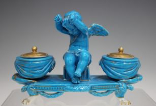 A turquoise glazed porcelain double inkwell, late 19th century, modelled as a cupid seated between