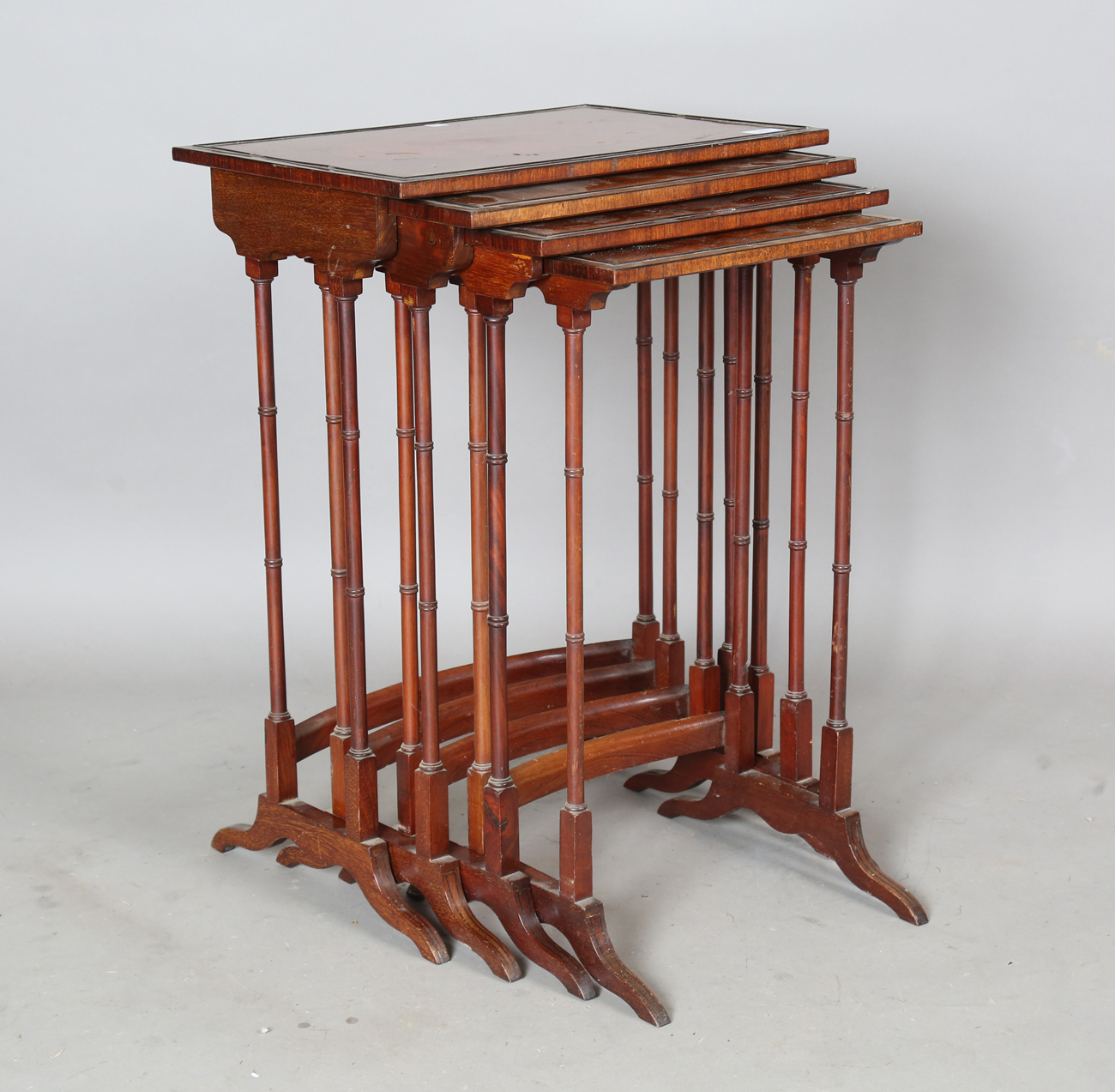 An Edwardian mahogany quartetto nest of occasional tables, each with an oval amboyna reserve and