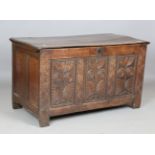A late 17th century oak coffer with hinged lid, the triple panel front later carved with flowerheads