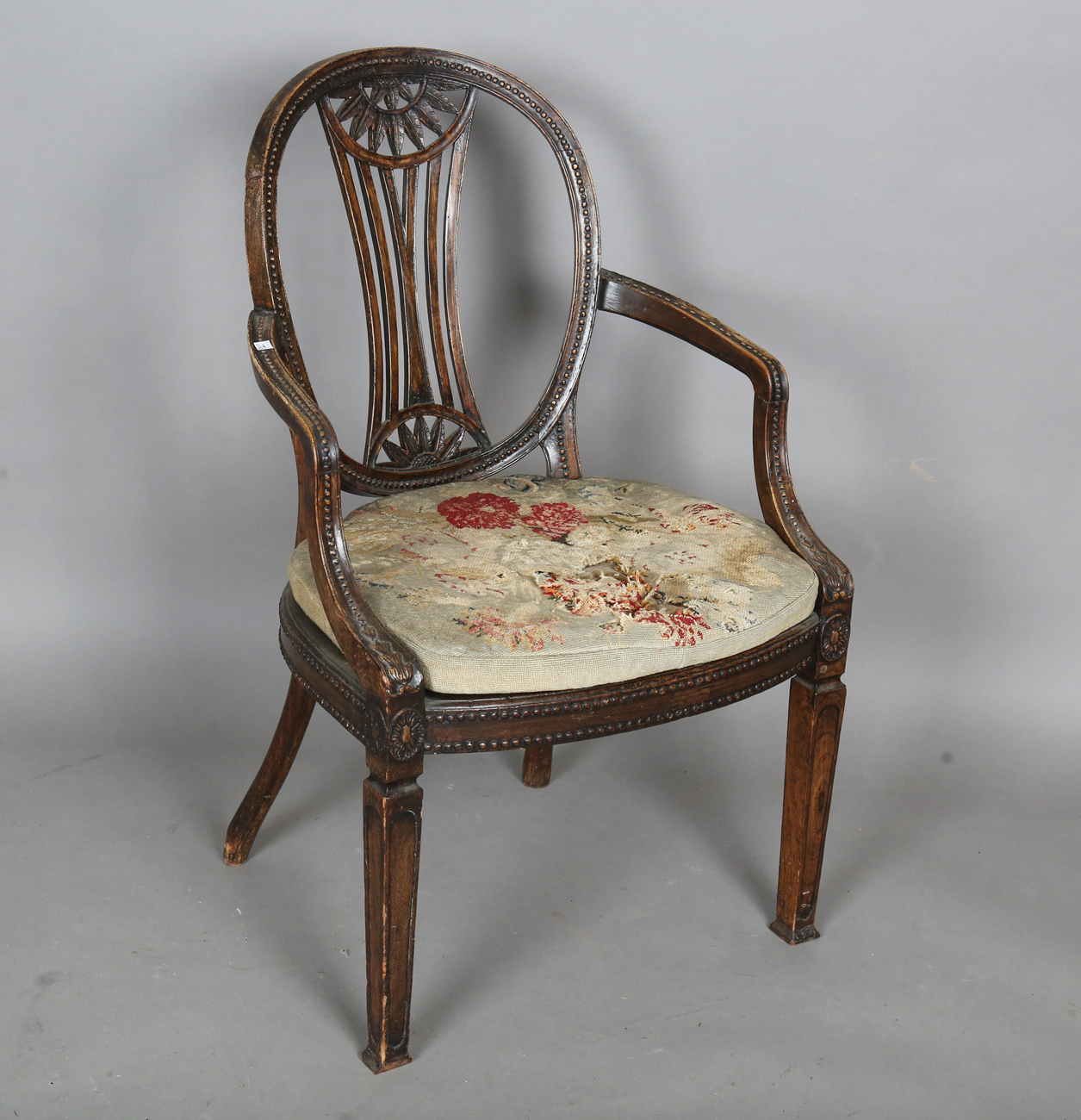 A late George III Neoclassical walnut framed elbow chair with a beaded frame and caned seat,
