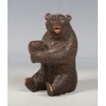 An early 20th century Black Forest softwood novelty pipe holder, carved as a seated bear, height