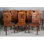 A set of eight George IV mahogany hall chairs, each panelled back with a central painted heraldic