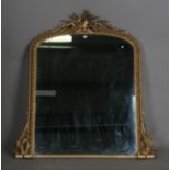 A late Victorian gilt composition arched overmantel mirror, the leaf and ribbon moulded frame