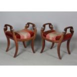 A pair of early Victorian mahogany framed stools with shaped handrests and turned finials, on