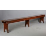 A pair of late 19th century stained pine benches, each raised on three shaped supports, height 47.