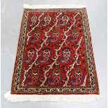A small Persian rug, late 20th century, the red field with overall diagonal tendrils and boteh,