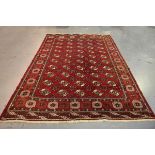 A Turkestan style carpet, mid-20th century, the claret field with overall offset guls, within a