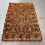 An Afghan rug, early 20th century, the faded claret field with two columns of hooked medallions,