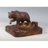An early 20th century Black Forest carved softwood pipe smoker's compendium, mounted with a prowling