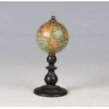 A late 19th century miniature table globe, raised on an ebonized turned wooden pedestal, diameter of