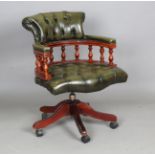 A late 20th century stained hardwood and buttoned green leather revolving tub back desk chair,