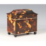 An early 19th century tortoiseshell tea caddy of sarcophagus form, raised on spherical ebonized