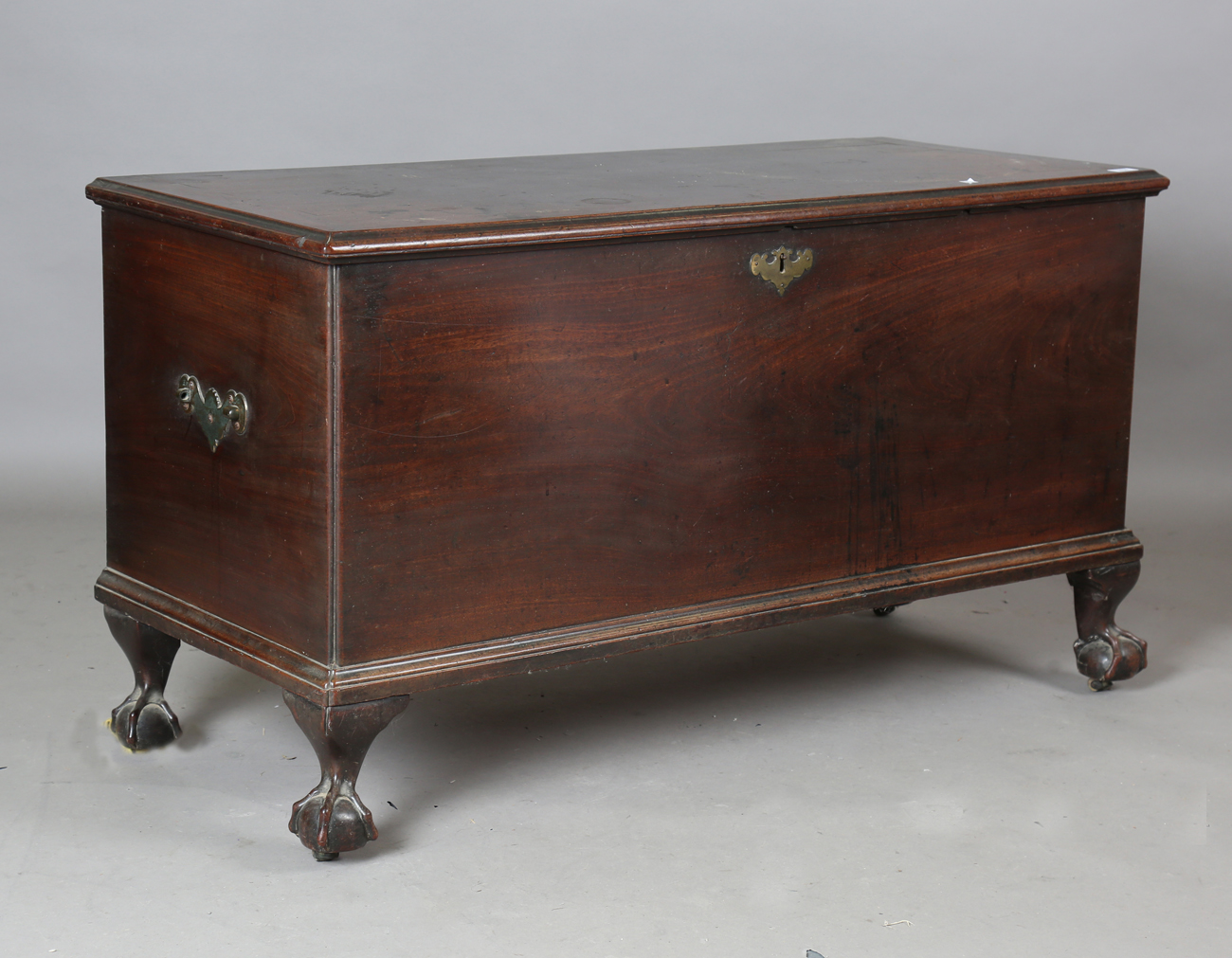 A George III mahogany trunk, the hinged lid above applied handles (one missing), raised on carved