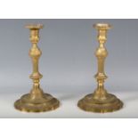 A pair of 18th century style cast ormolu candlesticks with overall foliate decoration, each raised