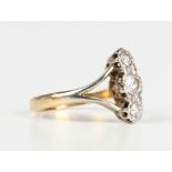 A gold and diamond three stone ring, mounted with a row of circular cut diamonds between 'V'