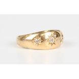 An 18ct gold and diamond three stone ring, star gypsy set with a row of cushion cut diamonds,