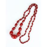 A single row necklace of oval cherry coloured imitation amber beads, first half of the 20th century,