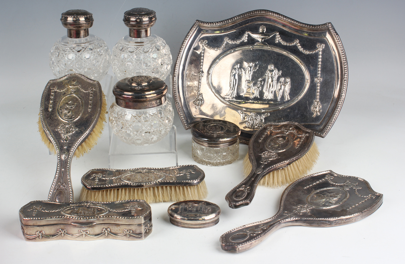 An Edwardian silver ten-piece dressing table set, embossed with classical figures and bellflower