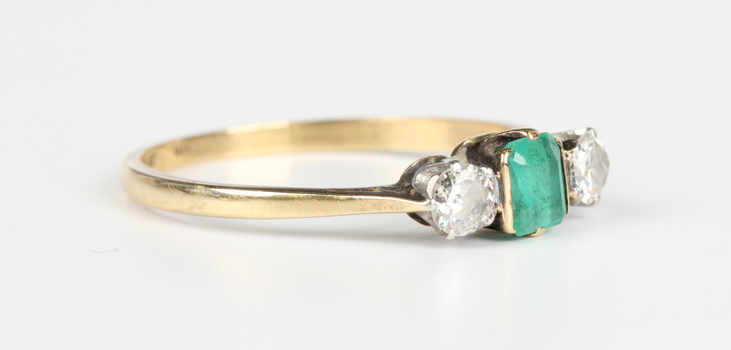 A gold, platinum, emerald and diamond three stone ring, mounted with a rectangular cut emerald