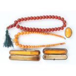 A single row necklace of graduated spherical opaque varicoloured butterscotch coloured amber beads
