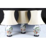 A set of three modern Chinese porcelain table lamps, the ovoid bodies decorated with peacocks within