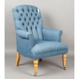 A modern armchair, upholstered in buttoned blue fabric, on turned legs and brass castors, height
