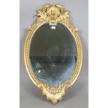 A 20th century rococo style gilt composition oval wall mirror with a shell surmount and scroll