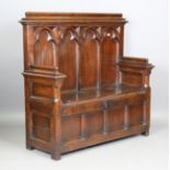 An early 20th century Gothic Revival oak settle, the heavily carved tracery panel back above a