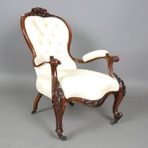 A mid-Victorian walnut showframe armchair, the top rail finely carved with a foliate cartouche,