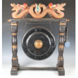 A 20th century Eastern carved and painted wooden dinner gong, height 70cm, width 53cm.Buyer’s