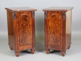 A pair of Victorian mahogany pedestal cabinets, each fitted with an arched panel door enclosing