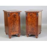 A pair of Victorian mahogany pedestal cabinets, each fitted with an arched panel door enclosing