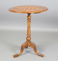 A late Victorian walnut oval games occasional table, the top inlaid with a chessboard, on a carved
