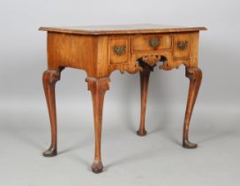A George I walnut and crossbanded kneehole lowboy, fitted with three drawers above a fretwork apron,