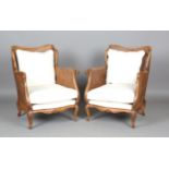A pair of mid-20th century French beech showframe bergère armchairs, upholstered in cream fabric,