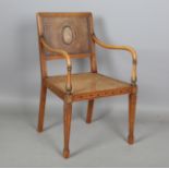 An early 20th century Neoclassical Revival beech framed bergère elbow chair, the caned back