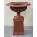 An early 20th century patinated cast iron garden urn of reeded campana form, raised on a square