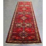 A Hamadan runner, North-west Persia, late 20th century, the red field with a column of medallions,