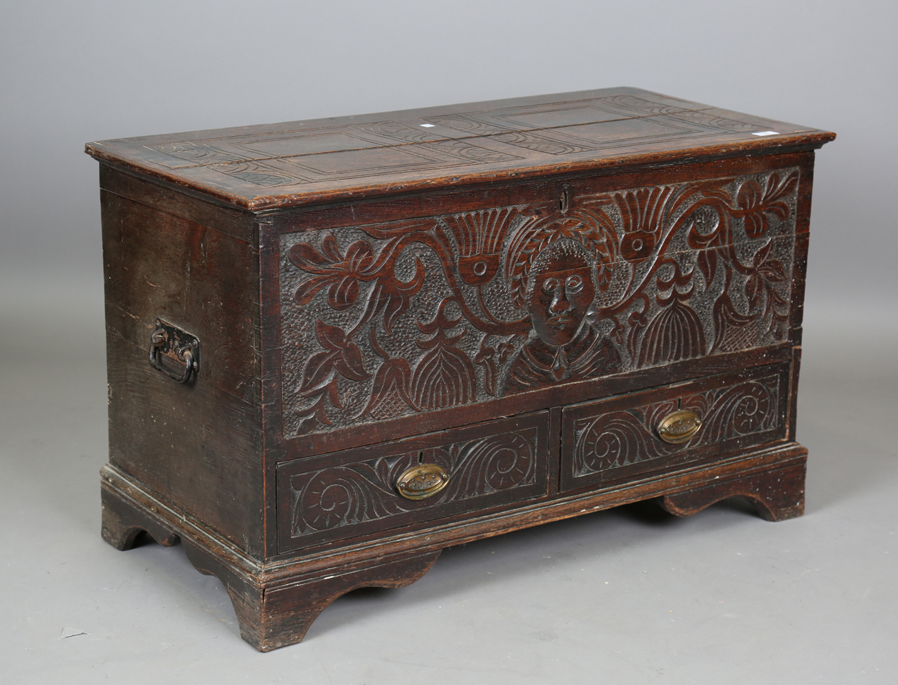 A 19th century oak mule chest, the hinged lid above a carved front, fitted with two drawers,