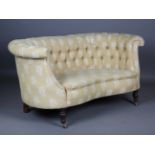 A late Victorian buttoned tub back settee, upholstered in patterned yellow fabric, on turned legs
