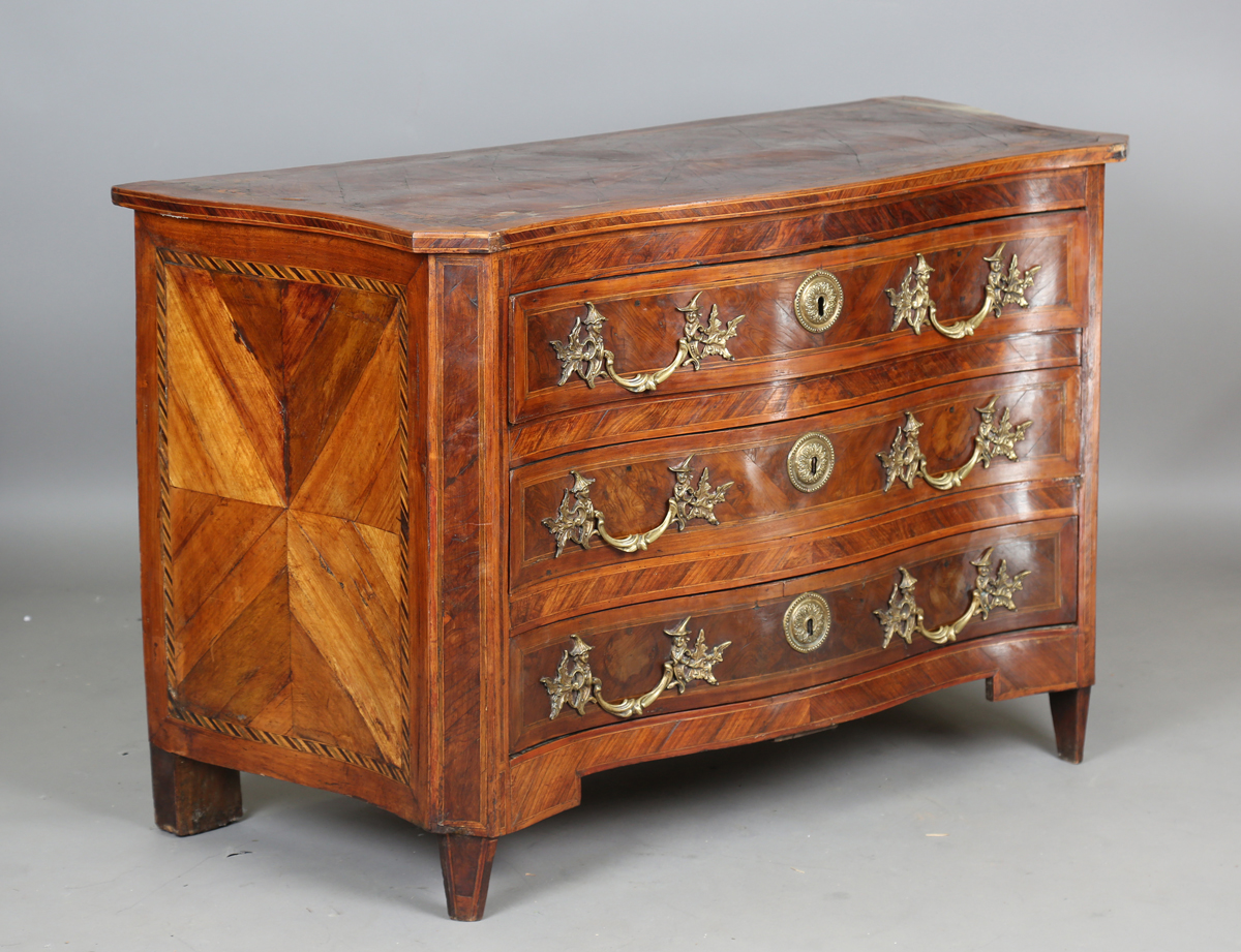 An early 18th century Italian yew and walnut three-drawer serpentine fronted commode with