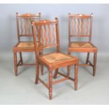 A set of three Edwardian Arts and Crafts oak-framed side chairs with wavy comb backs and inset