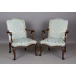 A pair of 20th century George II style walnut framed armchairs, upholstered in foliate patterned