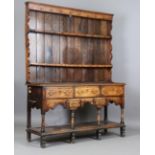 An 18th century provincial oak and elm dresser, the later shelf rack above three drawers, two